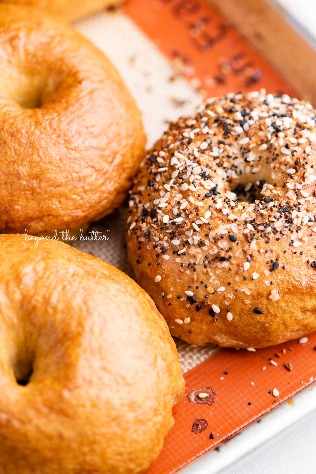 Silicone mat lined baking sheet with just baked homemade bagels | © Beyond the Butter®