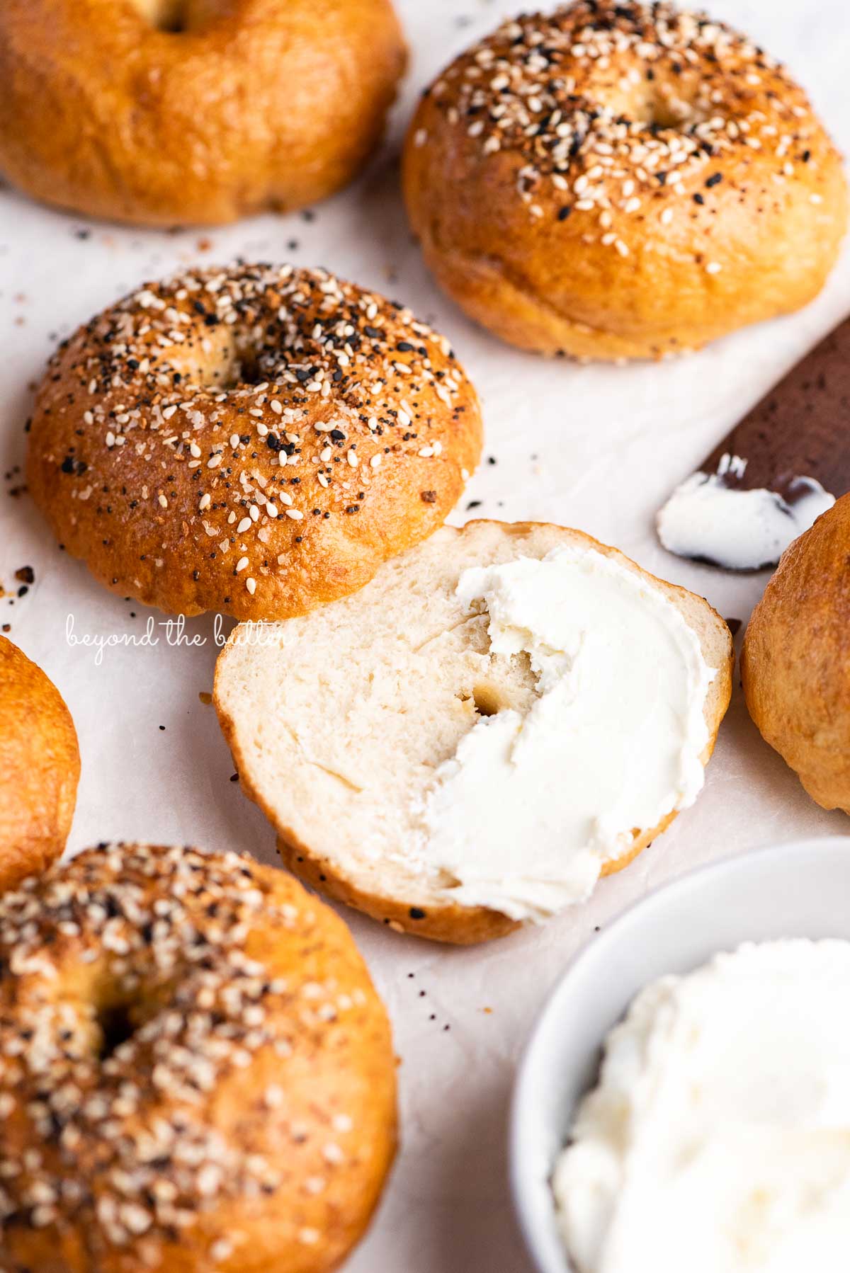 Easy homemade bagel sliced with cream cheese partially spread over the top | © Beyond the Butter®