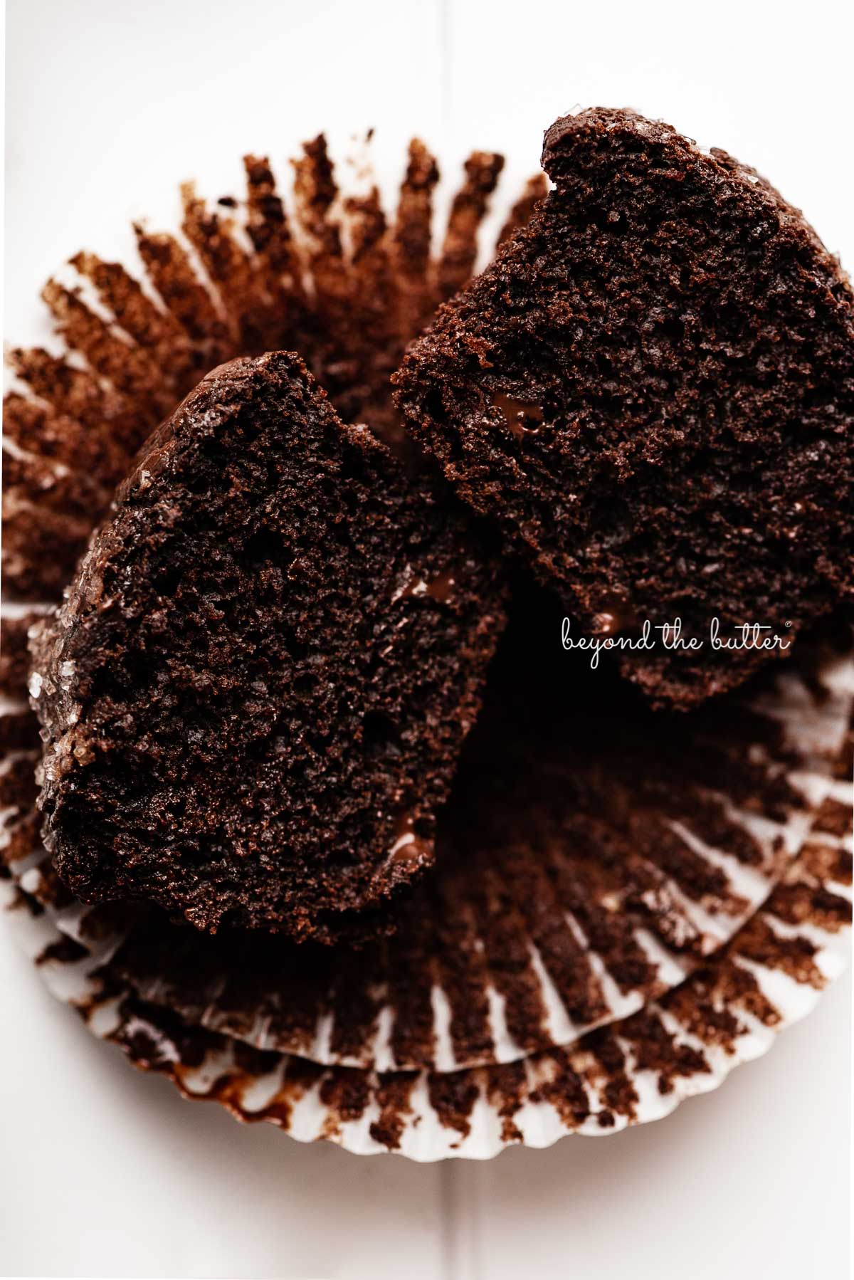 Double chocolate muffin cut in half on opened muffin liners | © Beyond the Butter®