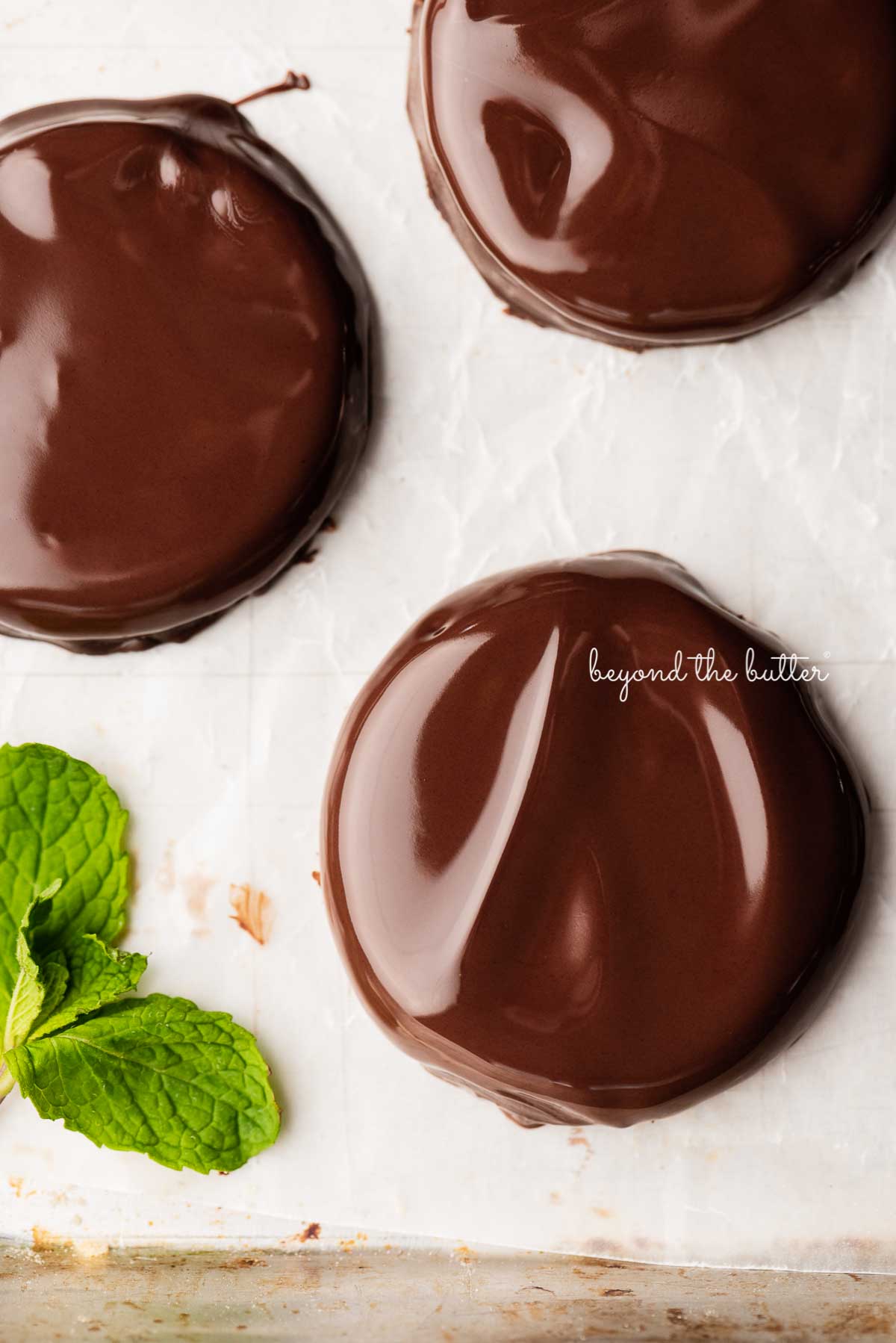 Copycat Girl Scout thin mint cookies just dipped in chocolate and placed on a wax paper lined baking sheet | © Beyond the Butter®