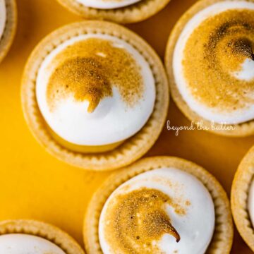 Mini lemon meringue pies on a yellow background | © Beyond the Butter®