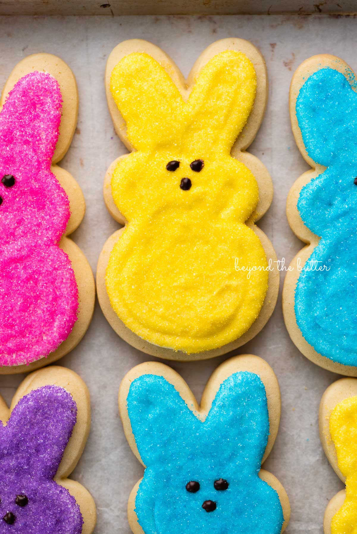 Easter bunny cut out sugar cookies on a parchment paper lined baking sheet.