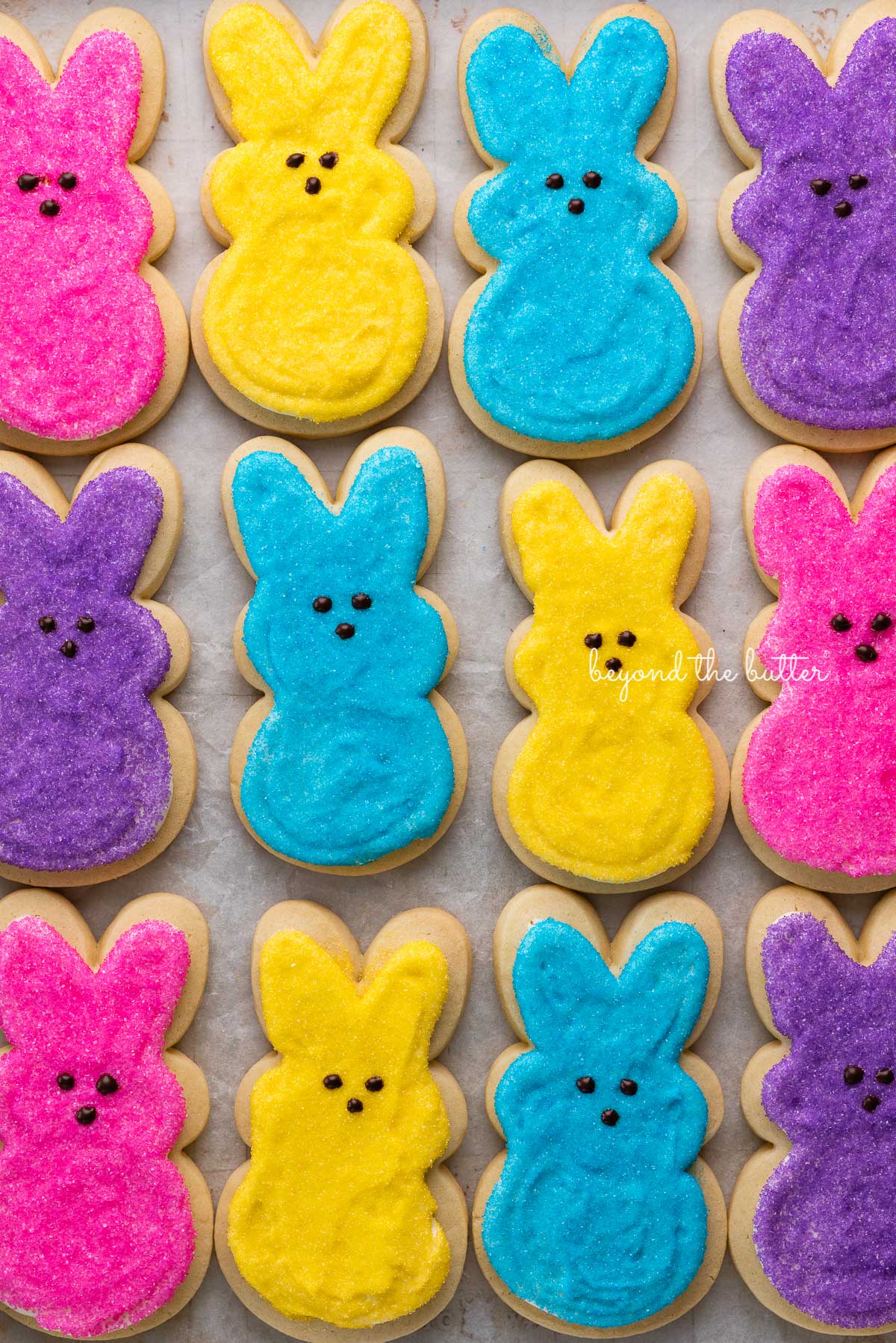 Easter bunny cut out sugar cookies on a parchment paper lined baking sheet | © Beyond the Butter®