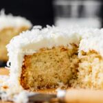 Sliced single layer coconut cake with black background.