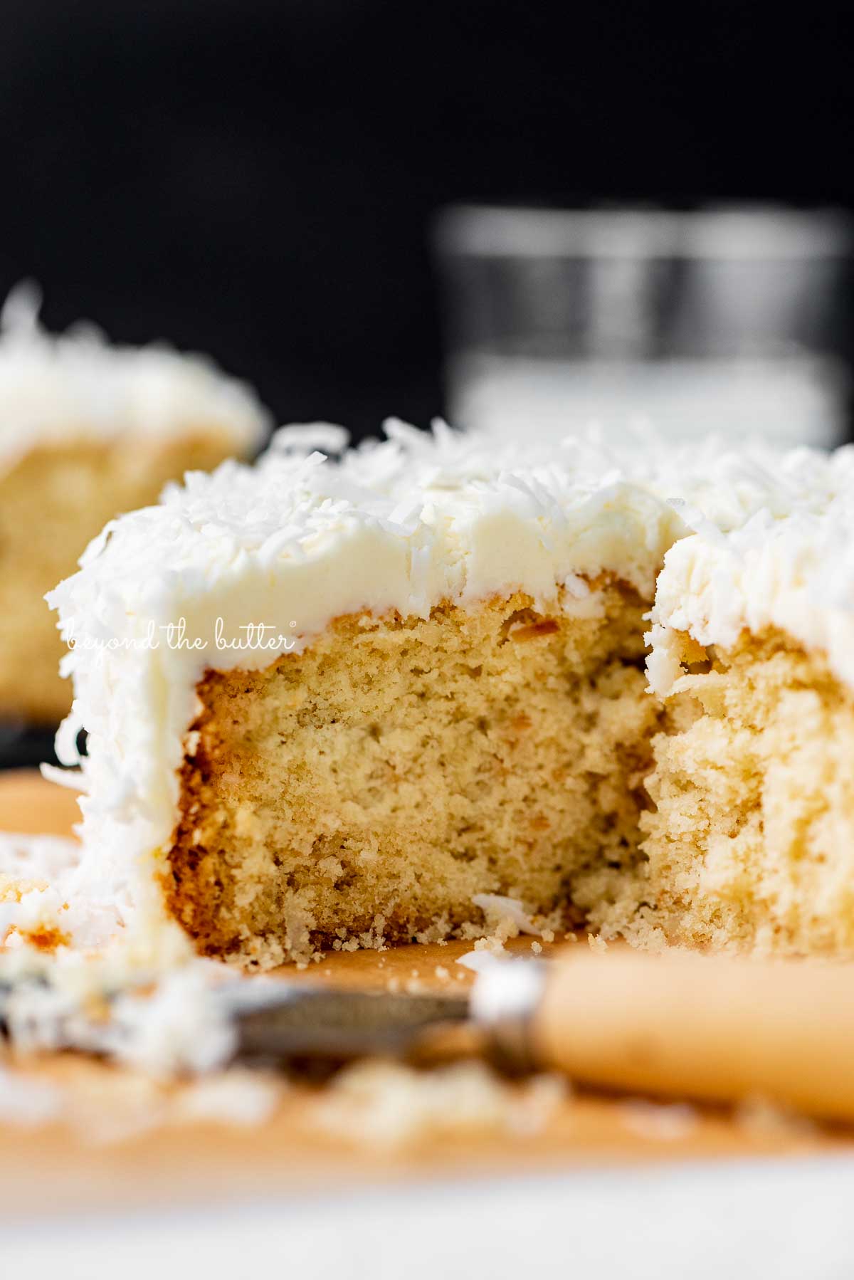 Sliced single layer coconut cake with black background | © Beyond the Butter®
