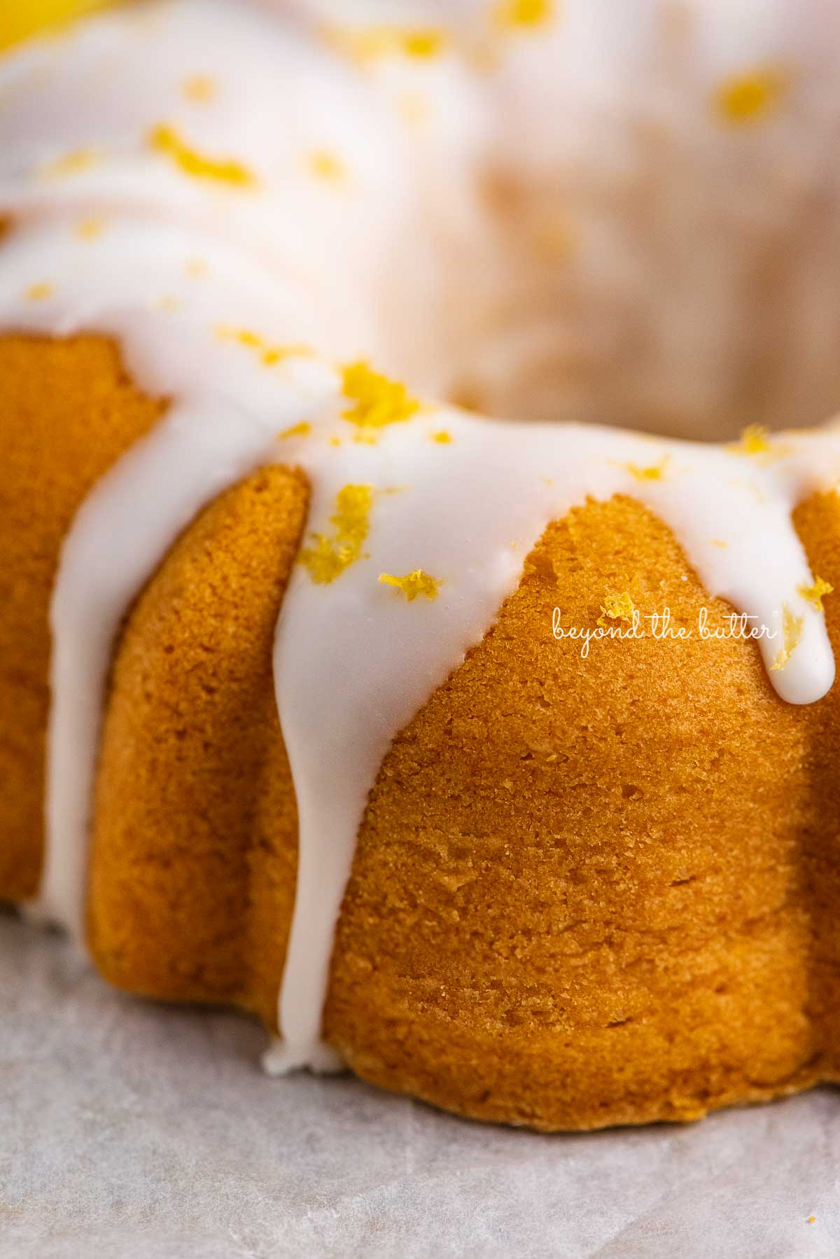 Close up image of lemon glazed small lemon cream cheese pound cake garnished with lemon zest | © Beyond the Butter®