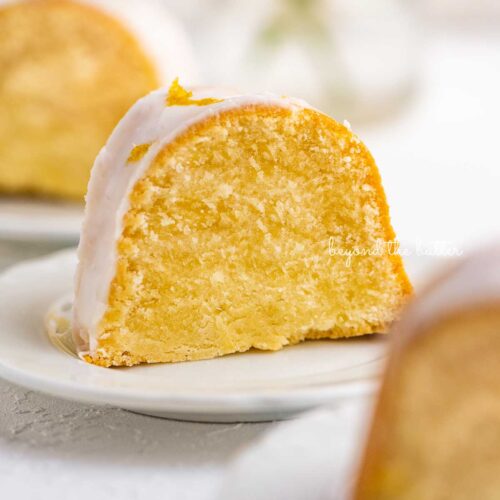 Small lemon cream cheese pound cake slice on a small dessert plate on white background.