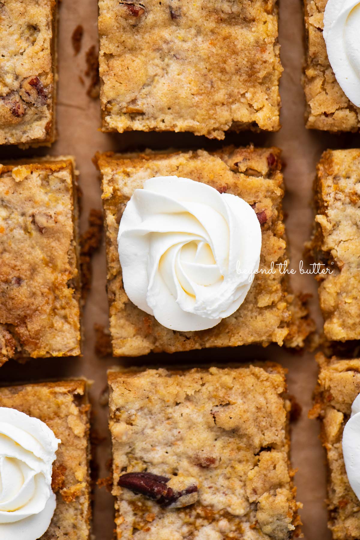 Sliced pumpkin pie cake bars on parchment paper background | © Beyond the Butter®
