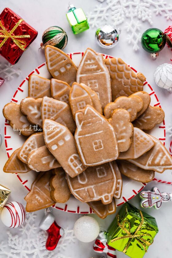 Christmas themed dessert plate filled with soft and chewy gingerbread cut out cookies with ornaments around it on a white marbled background | © Beyond the Butter®