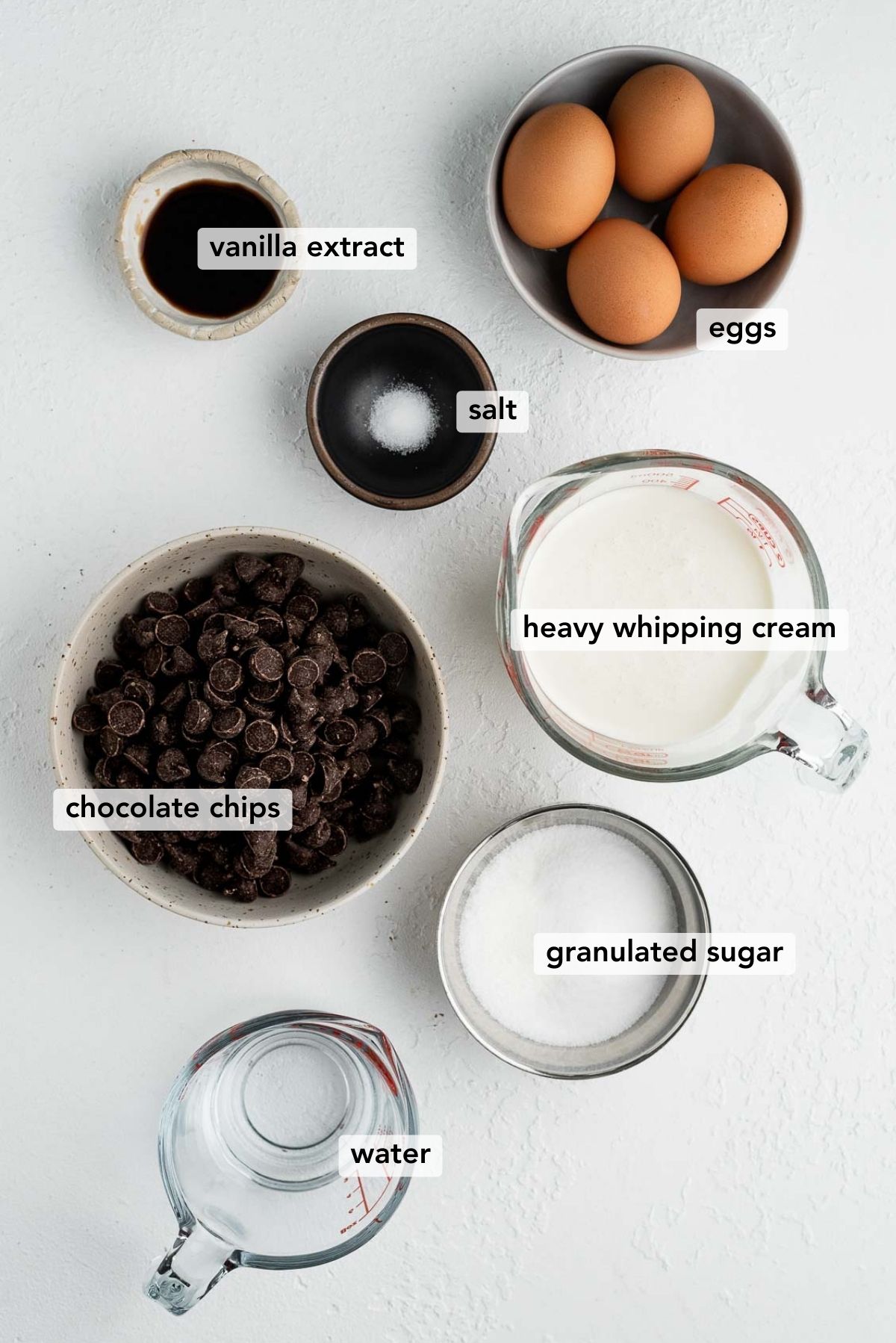 Ingredients needed to make easy blender chocolate mousse on white textured background.