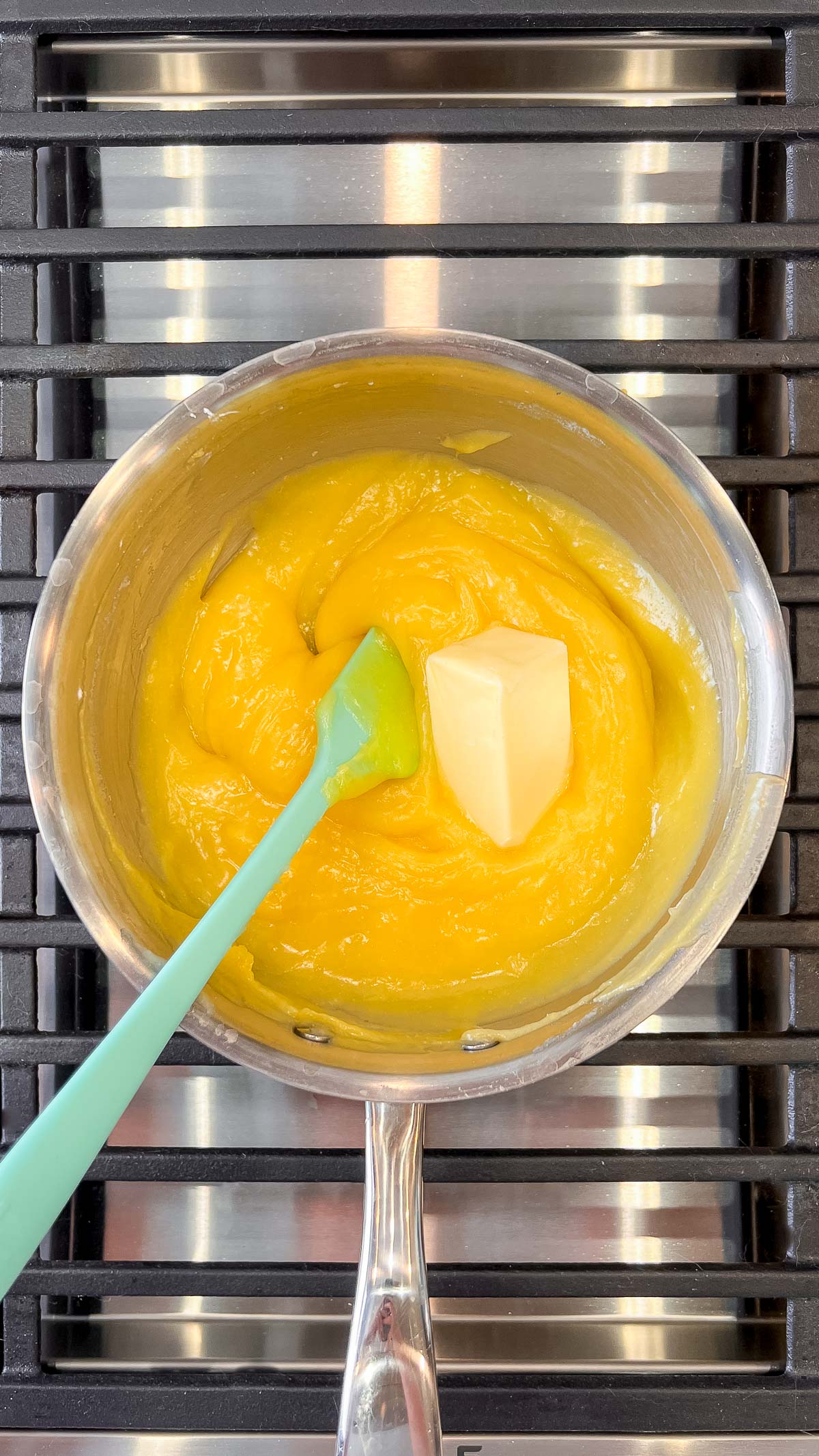 Adding butter to lemon cream pie filling mixture in a medium saucepan.