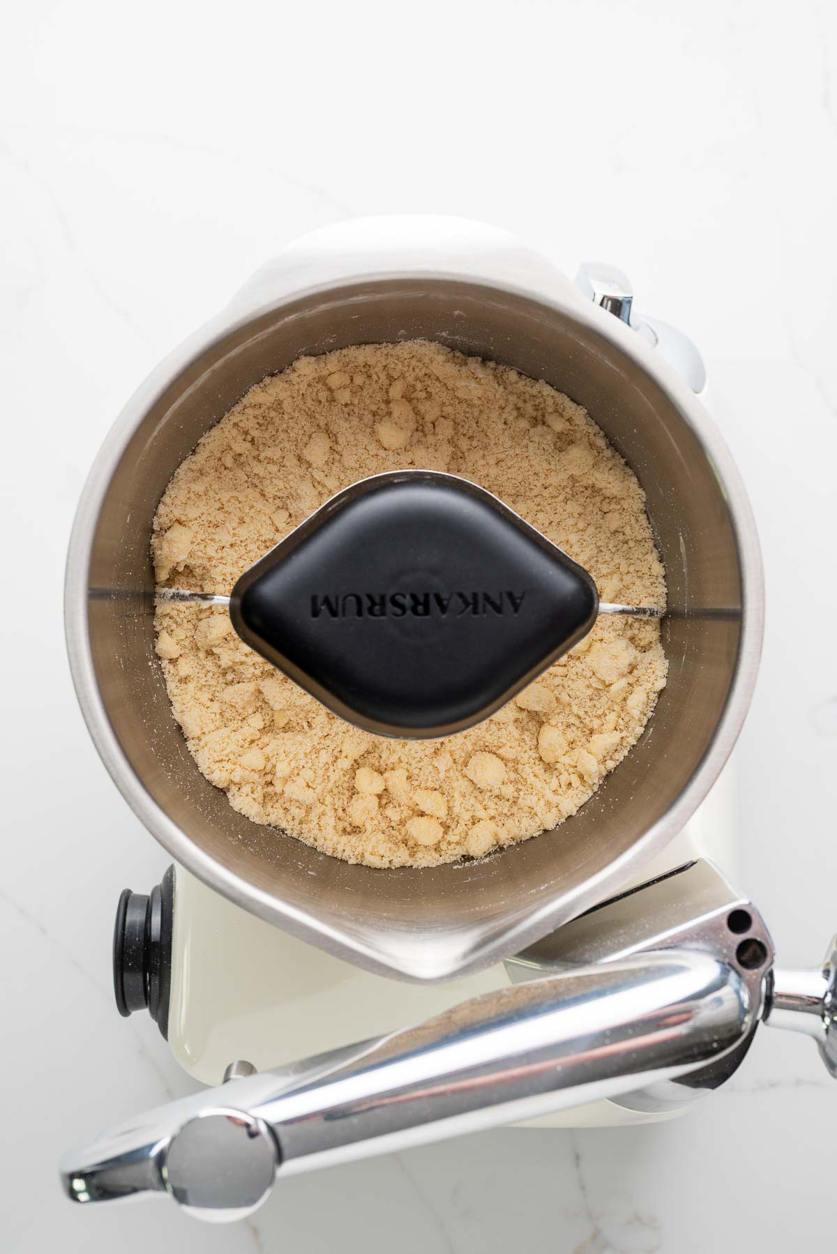 Flour, salt, sugar, and cold cubed butter mixed together in a creme light colored ankarsrum assistent original mixer and stainless steel beater bowl with their new premium beater set.
