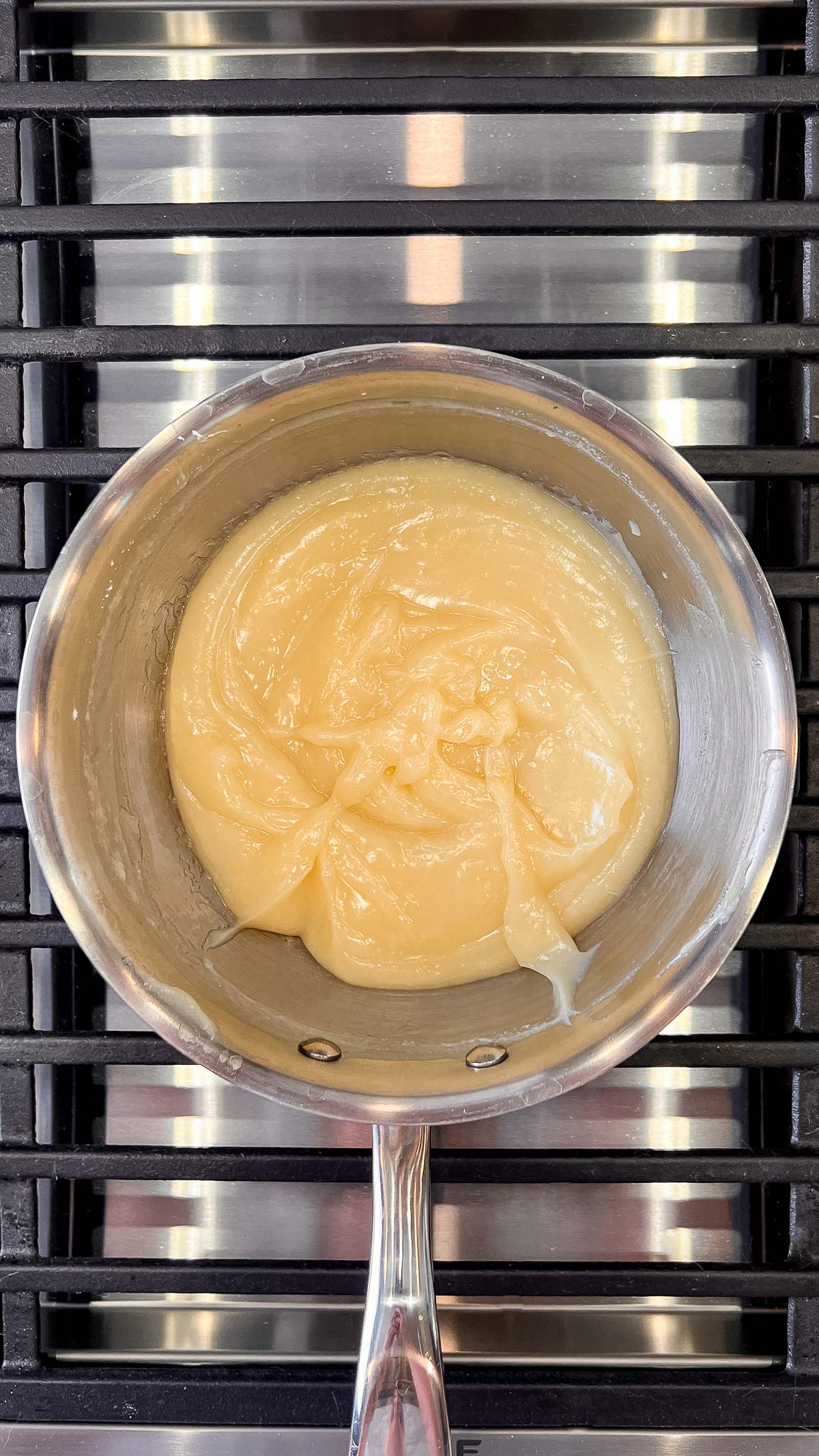 Thickened lemon cream pie filling in a medium saucepan over a medium high heat grill.