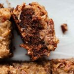 Sliced German chocolate sheet cake on its side next to other slices in a parchment paper lined ceramic baking pan.