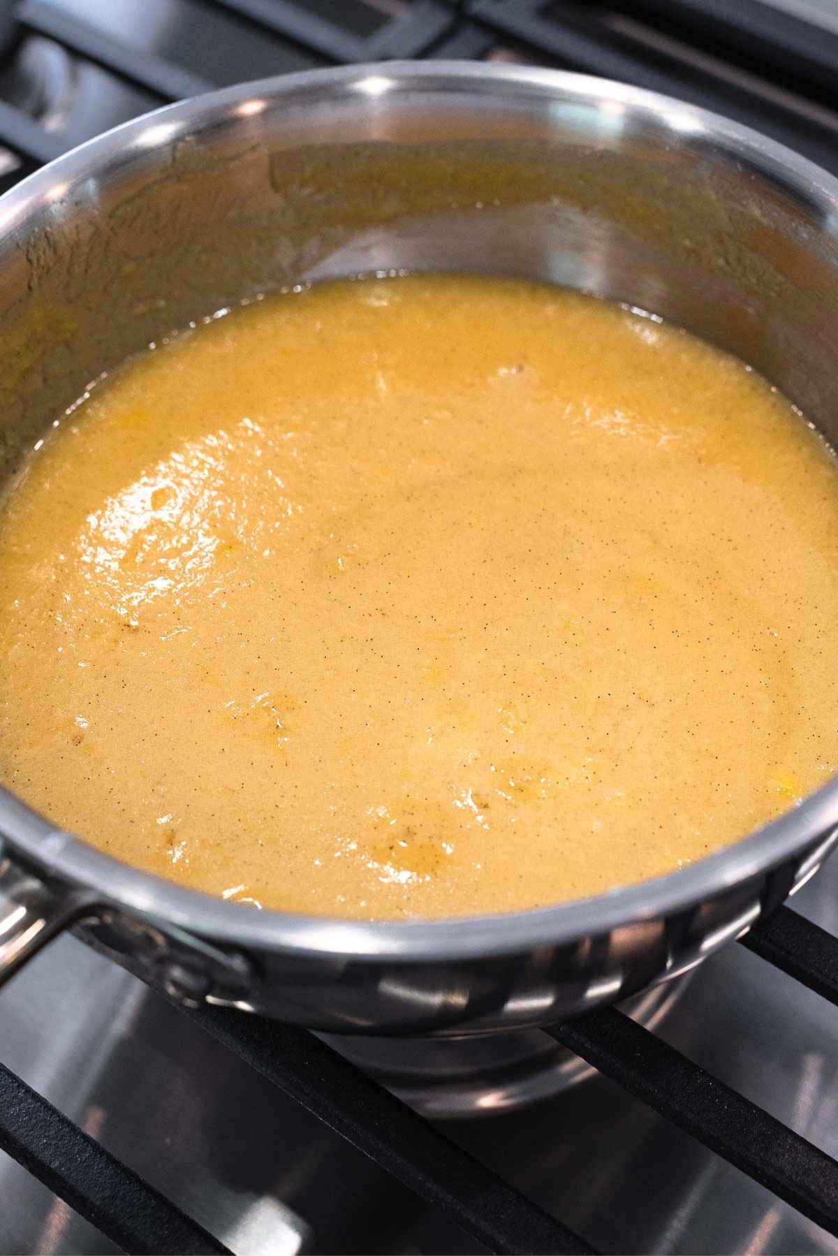 Thickened butter, evaporated milk, egg yolks, sugar, and extracts in a stainless steel saucepan.